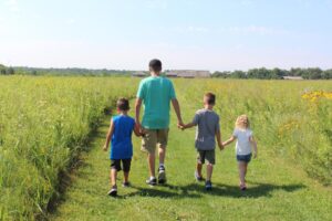 Family walking hand-in-hand through a field in Greater Lafayette